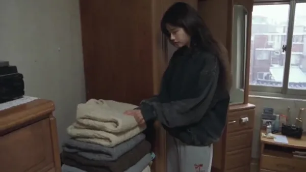 首尔旧公寓卧室：穿褪色紫T恤的年轻女子