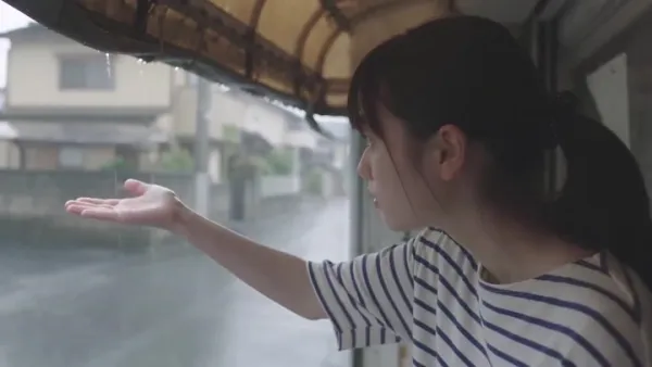 细雨中的日本社区：传统巴士站下等车的年轻女孩